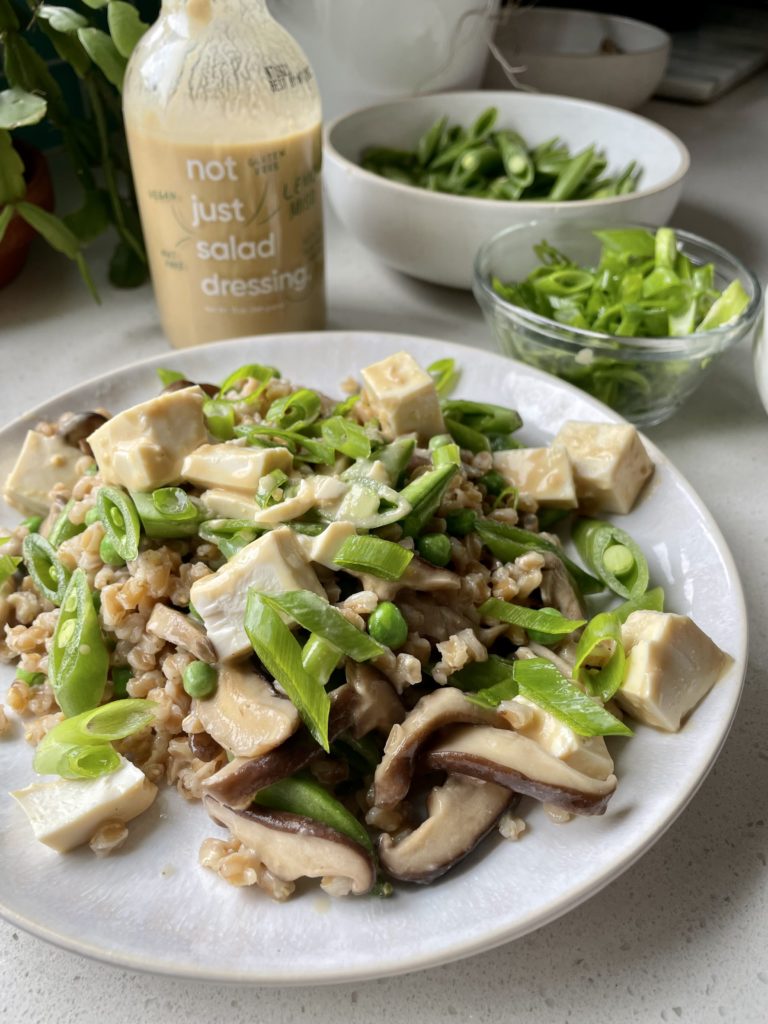plate of farotto with spring vegetables and a bottle of lemon miso not just salad dressing